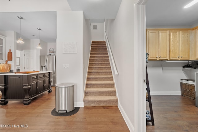 stairs featuring visible vents, baseboards, and wood finished floors