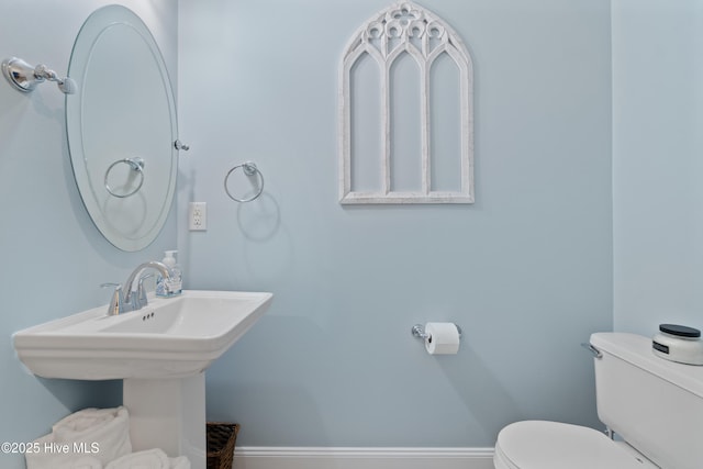 bathroom featuring toilet, baseboards, and a sink