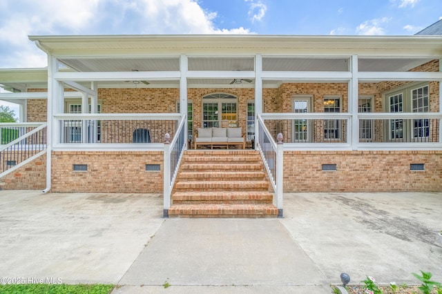 doorway to property featuring crawl space, brick siding, and covered porch