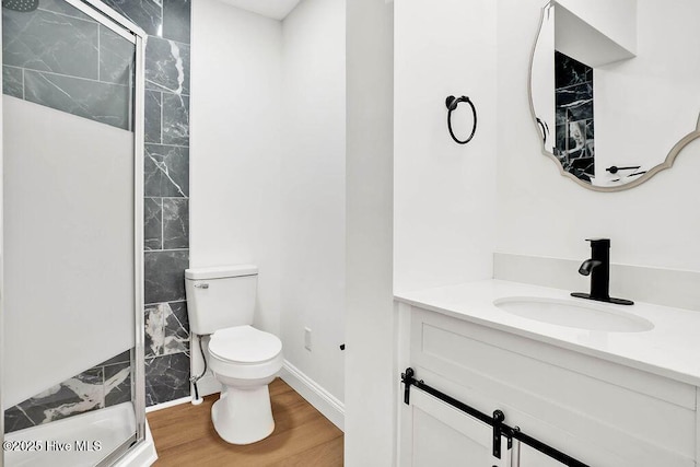 bathroom with vanity, a shower stall, toilet, and wood finished floors