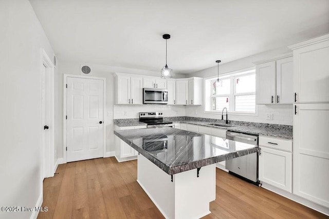 kitchen featuring a sink, light wood-style floors, appliances with stainless steel finishes, and white cabinetry