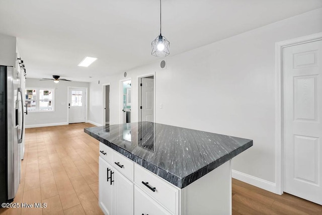 kitchen with a ceiling fan, stainless steel refrigerator with ice dispenser, white cabinetry, decorative light fixtures, and light wood-type flooring