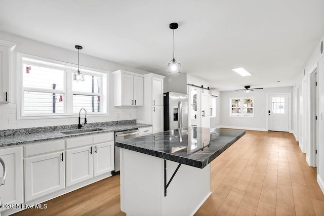 kitchen with a sink, stainless steel appliances, a barn door, and white cabinetry