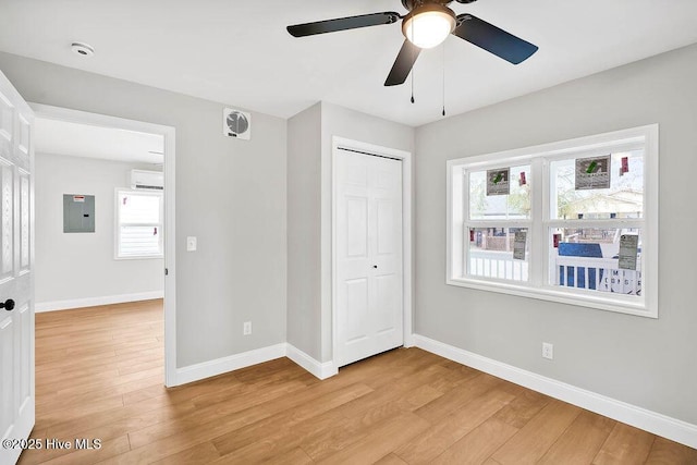 unfurnished bedroom featuring electric panel, light wood-style floors, and baseboards