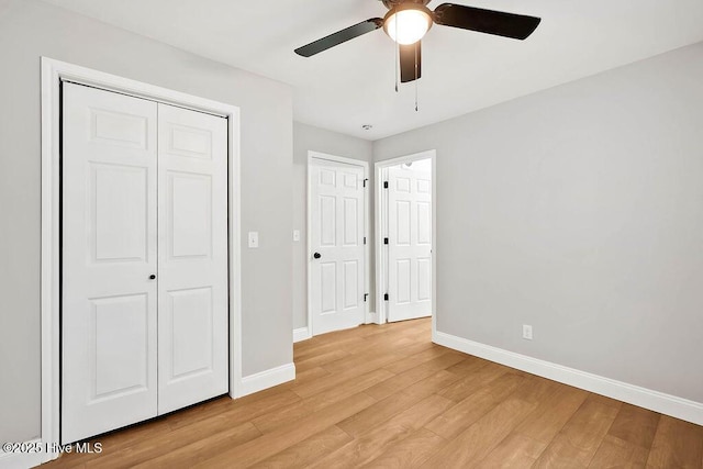 unfurnished bedroom featuring a closet, ceiling fan, light wood-type flooring, and baseboards