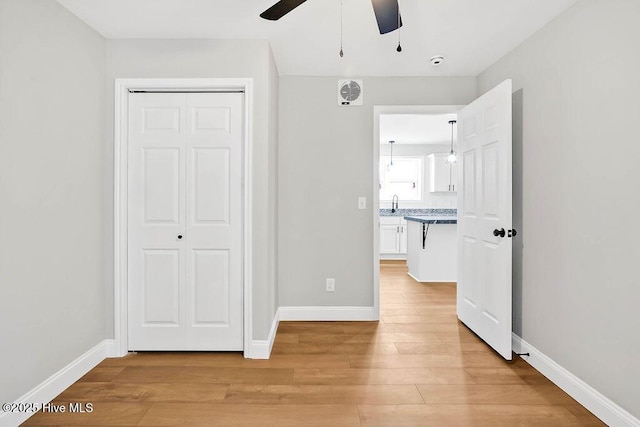 unfurnished bedroom with light wood-type flooring, a closet, baseboards, and a sink