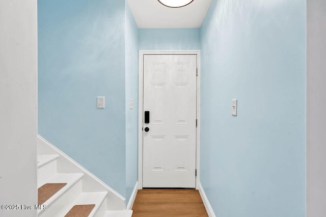 doorway to outside with baseboards, wood finished floors, and stairs