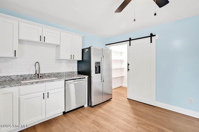 kitchen featuring a ceiling fan, a sink, light wood-style floors, appliances with stainless steel finishes, and tasteful backsplash