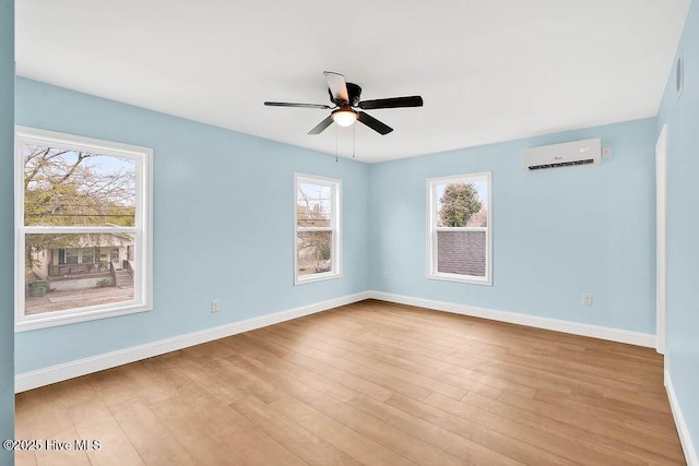 unfurnished room featuring a wall mounted air conditioner, baseboards, wood finished floors, and ceiling fan