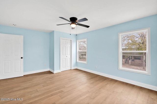 unfurnished bedroom featuring a closet, a ceiling fan, baseboards, and wood finished floors