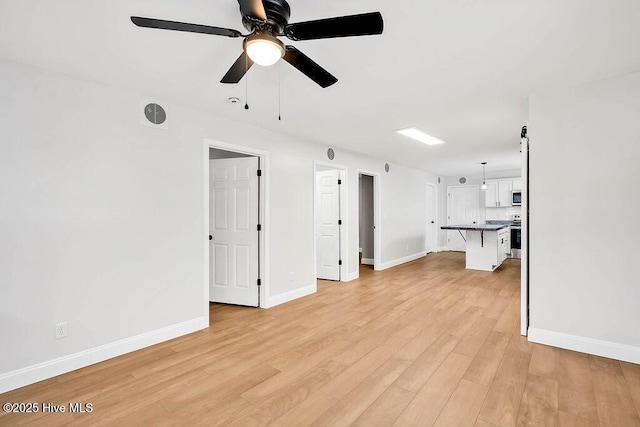 unfurnished living room featuring visible vents, baseboards, light wood-style flooring, and a ceiling fan