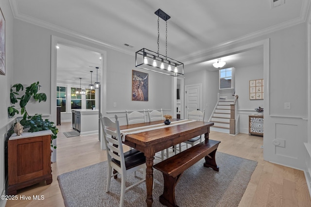 dining space with visible vents, stairs, wainscoting, crown molding, and light wood-type flooring