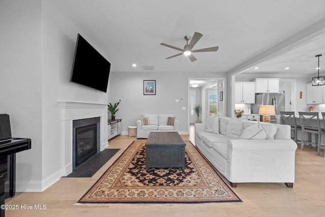 living area featuring visible vents, baseboards, light wood-style flooring, a fireplace with flush hearth, and recessed lighting