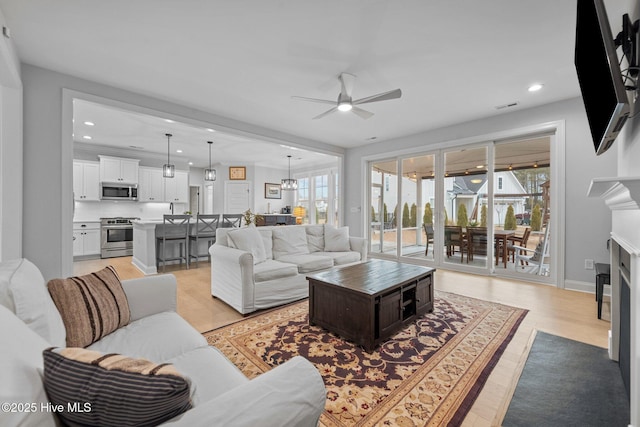 living area featuring recessed lighting, a fireplace, light wood-type flooring, and ceiling fan