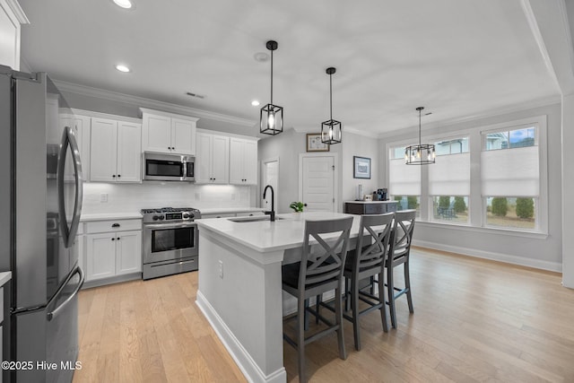 kitchen featuring tasteful backsplash, light wood-type flooring, light countertops, appliances with stainless steel finishes, and a sink