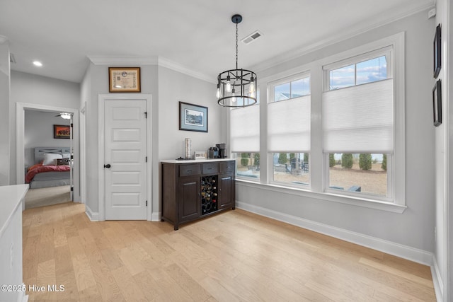 dining room with visible vents, baseboards, light wood-style floors, crown molding, and a chandelier