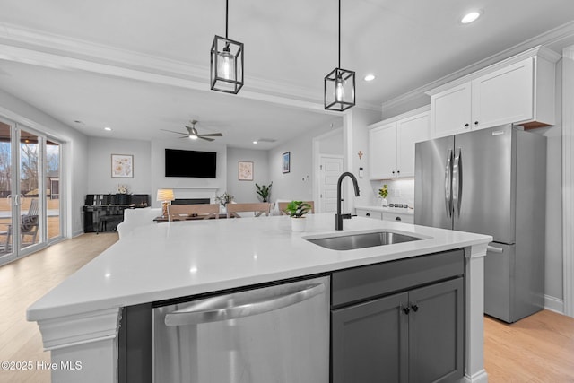 kitchen featuring an island with sink, a sink, appliances with stainless steel finishes, white cabinetry, and open floor plan