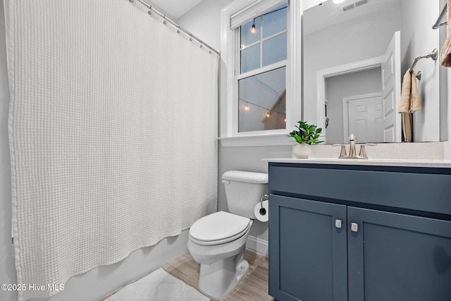 bathroom with baseboards, shower / bath combo with shower curtain, toilet, and vanity