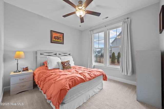 bedroom with visible vents, baseboards, light colored carpet, and a ceiling fan