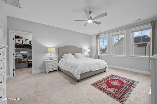 bedroom with visible vents, light carpet, and a walk in closet