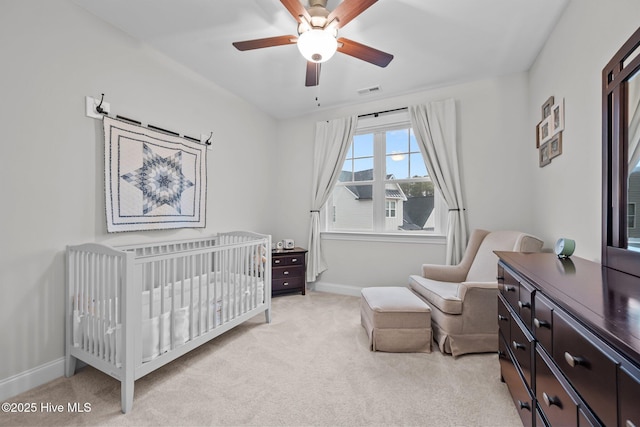 bedroom with a ceiling fan, a nursery area, light colored carpet, and baseboards