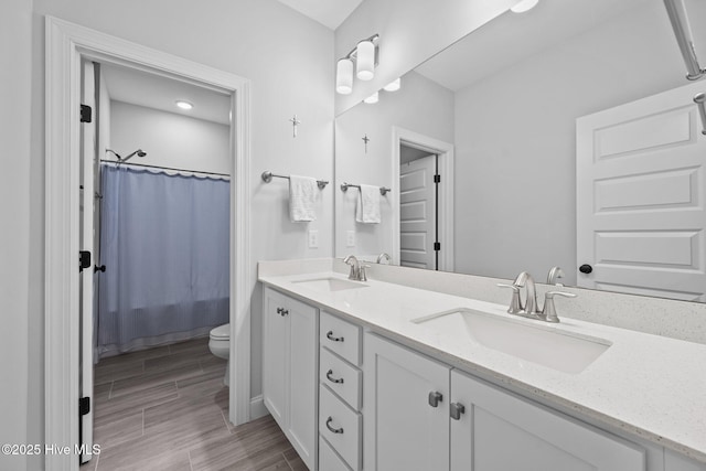 bathroom with double vanity, wood finish floors, toilet, and a sink