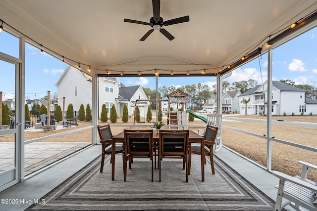 sunroom featuring lofted ceiling, plenty of natural light, a residential view, and ceiling fan