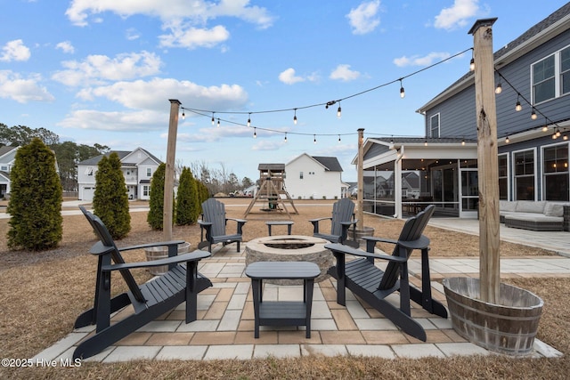 view of patio with a playground, a fire pit, and a sunroom