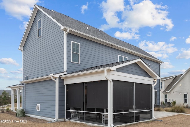 rear view of house featuring a shingled roof and a sunroom