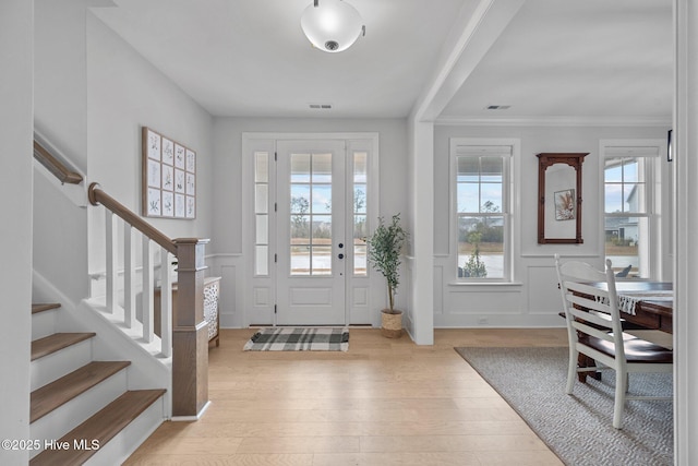 entrance foyer featuring stairs, wood finished floors, visible vents, and wainscoting