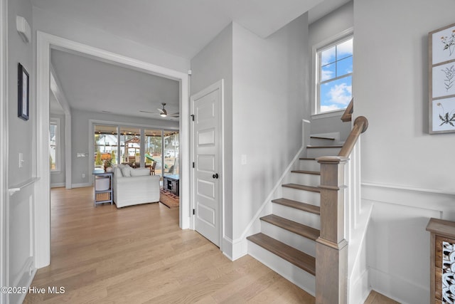 staircase with ceiling fan, baseboards, and wood finished floors