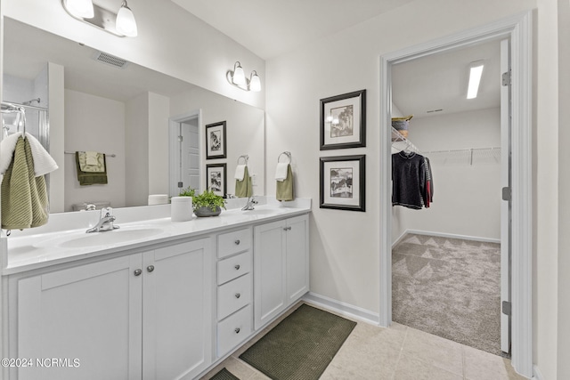 bathroom featuring double vanity, a spacious closet, visible vents, and a sink