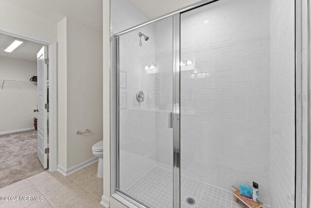 full bathroom with toilet, a stall shower, tile patterned flooring, baseboards, and a spacious closet