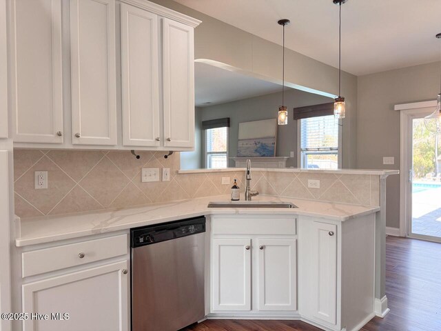 kitchen with tasteful backsplash, a peninsula, stainless steel dishwasher, white cabinets, and a sink