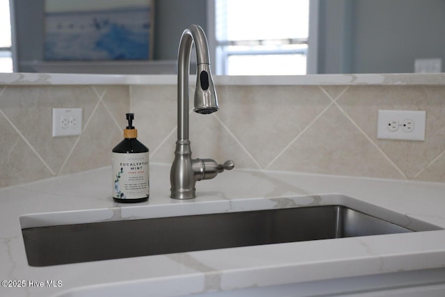 room details featuring light stone countertops, backsplash, and a sink