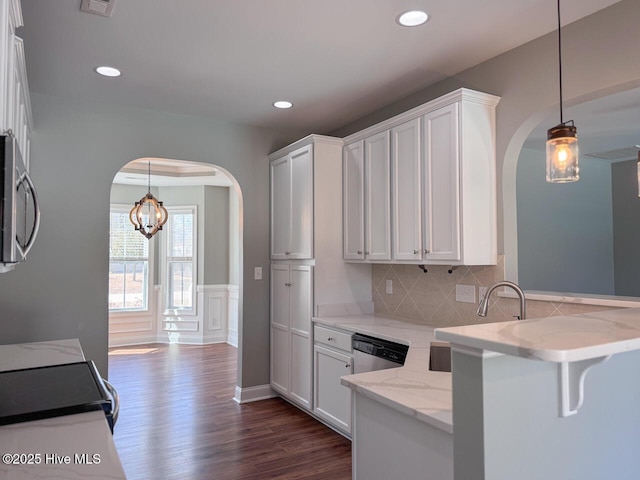 kitchen with stainless steel appliances, arched walkways, a peninsula, and white cabinetry