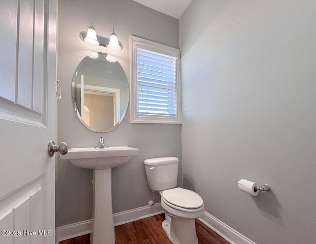 bathroom with baseboards, toilet, and wood finished floors