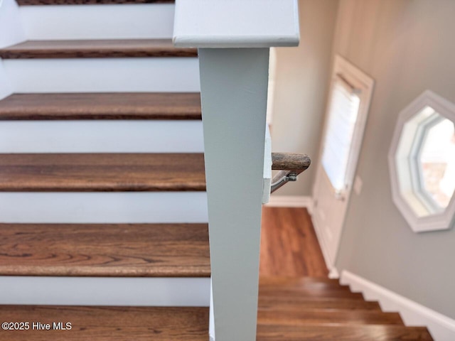 staircase featuring plenty of natural light, wood finished floors, and baseboards