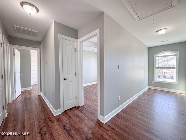 hall featuring visible vents, attic access, baseboards, and wood finished floors