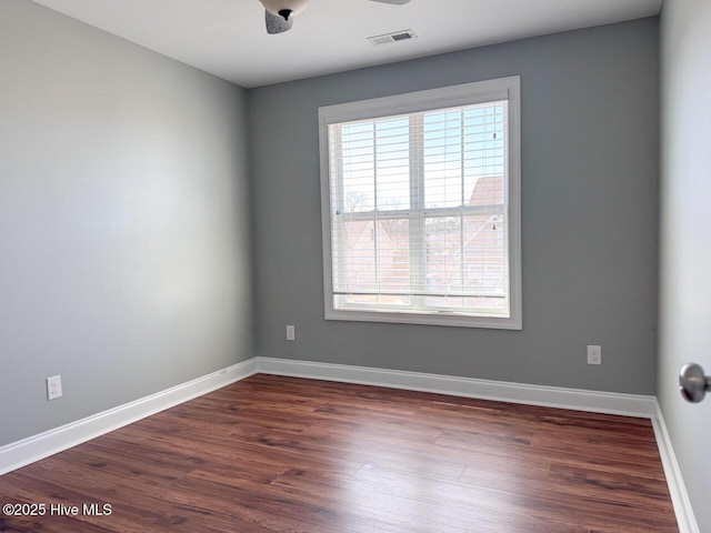 unfurnished room with visible vents, baseboards, and dark wood-style floors