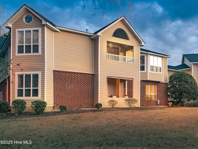 exterior space with a balcony, a yard, and brick siding