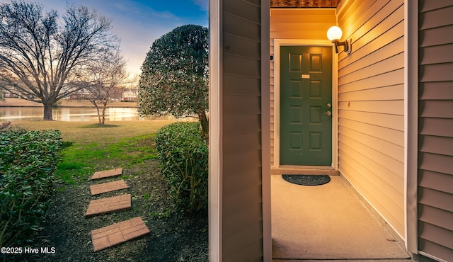 exterior entry at dusk with a yard and a water view