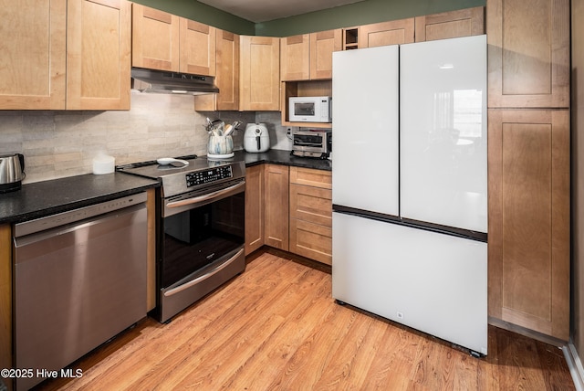 kitchen featuring dark countertops, light wood-type flooring, under cabinet range hood, and stainless steel appliances