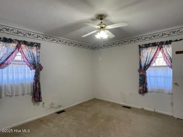 carpeted spare room featuring visible vents, baseboards, and a ceiling fan