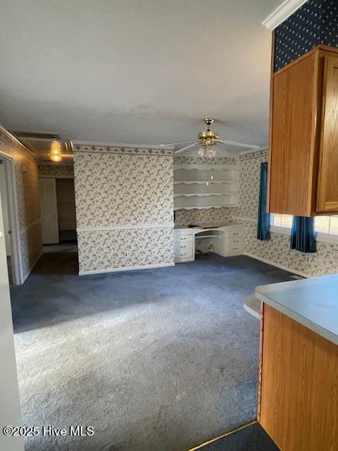 interior space with ceiling fan, brown cabinetry, and wallpapered walls