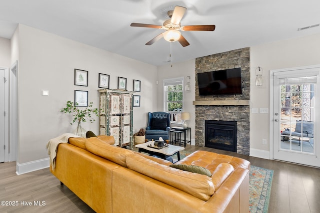 living room with a fireplace, wood finished floors, visible vents, and baseboards