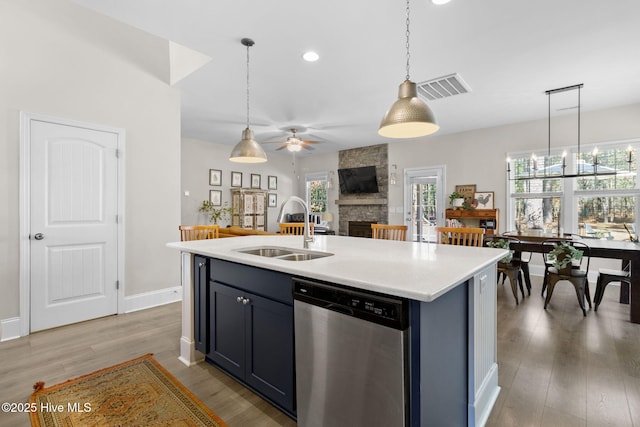 kitchen featuring visible vents, a fireplace, a sink, stainless steel dishwasher, and decorative light fixtures