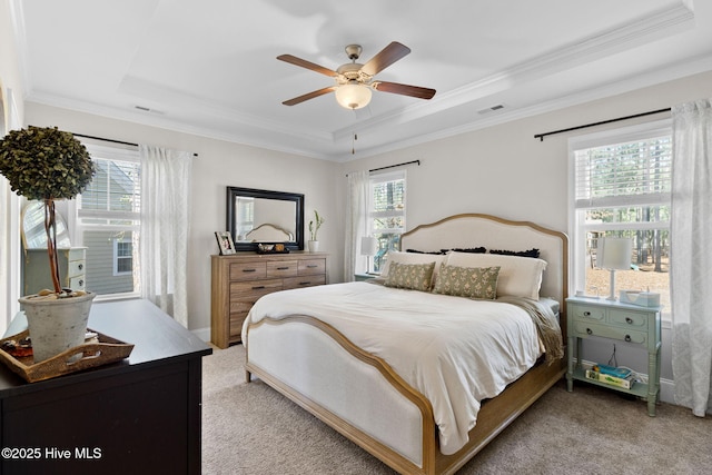 bedroom featuring a raised ceiling, crown molding, light colored carpet, and visible vents