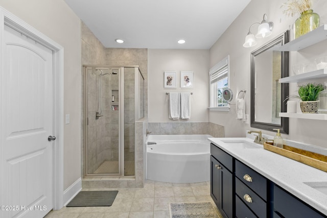 bathroom featuring a bath, a stall shower, double vanity, and a sink