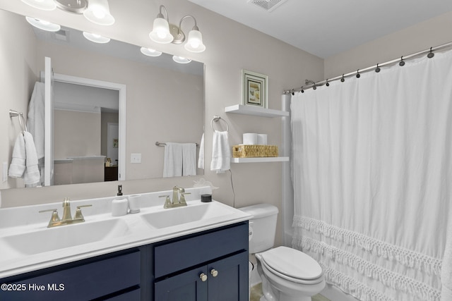 bathroom featuring double vanity, toilet, visible vents, and a sink